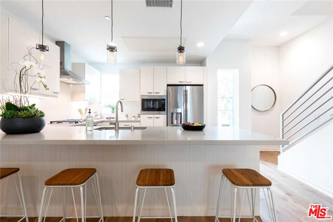 4821 1/2 Craner Avenue North Hollywood, CA 91601 - Photo 4 of 14 a kitchen with stainless steel appliances kitchen island granite countertop a sink a refrigerator and chairs