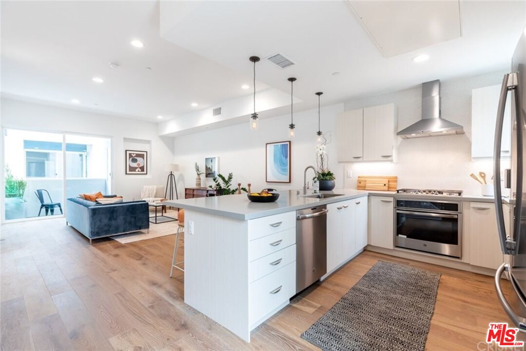 4821 1/2 Craner Avenue North Hollywood, CA 91601 - Photo 5 of 14 a kitchen with stainless steel appliances kitchen island granite countertop a stove a sink a refrigerator and white cabinets with wooden floor