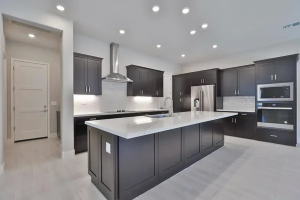 a large kitchen with stainless steel appliances a large counter top