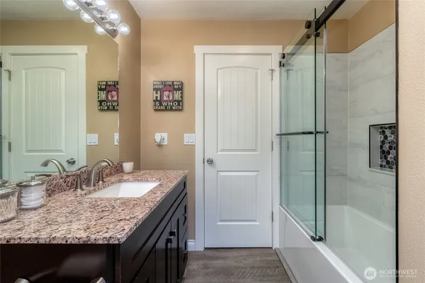 a bathroom with a granite countertop sink shower and a mirror