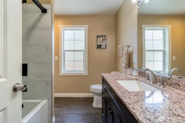 a bathroom with a granite countertop sink a toilet and bathtub