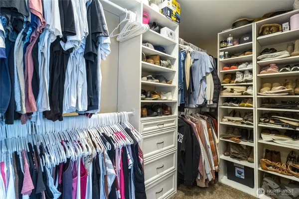 a view of walk in closet with clothes and shoes