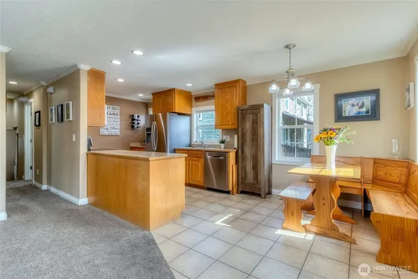 a kitchen with stainless steel appliances kitchen island granite countertop dining table chair and a refrigerator