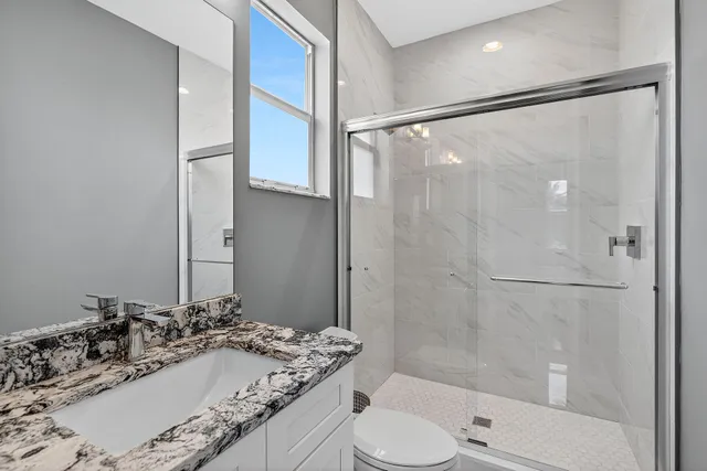 a bathroom with a granite countertop sink toilet and shower