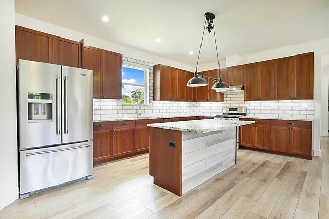 a kitchen with kitchen island granite countertop wooden cabinets and white appliances