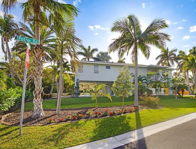 a view of a house with a yard and palm trees