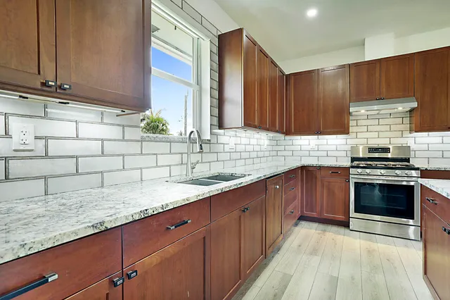 a kitchen with stainless steel appliances granite countertop wooden cabinets a stove and a sink