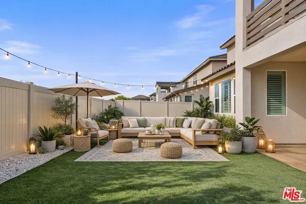 a view of a patio with couches table and chairs under an umbrella