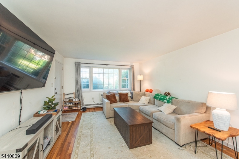 206 Main Street, Unit 42A Millburn, NJ 07041 - Photo 11 of 21 a living room with furniture a flat screen tv and a large window