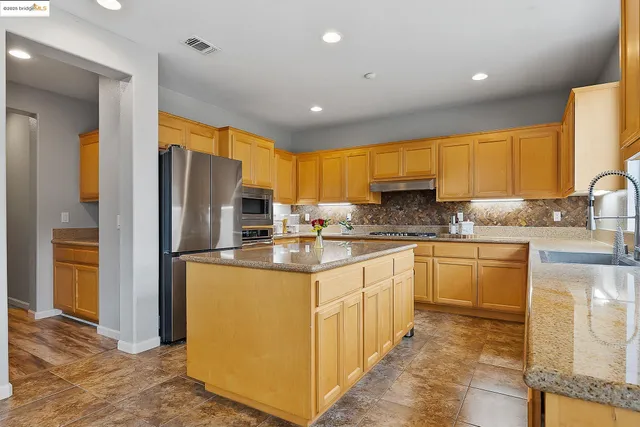 a kitchen with stainless steel appliances granite countertop a sink a stove and a refrigerator