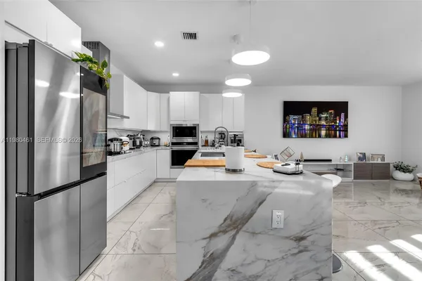 a large kitchen with kitchen island a refrigerator a stove a sink a dining table and chairs