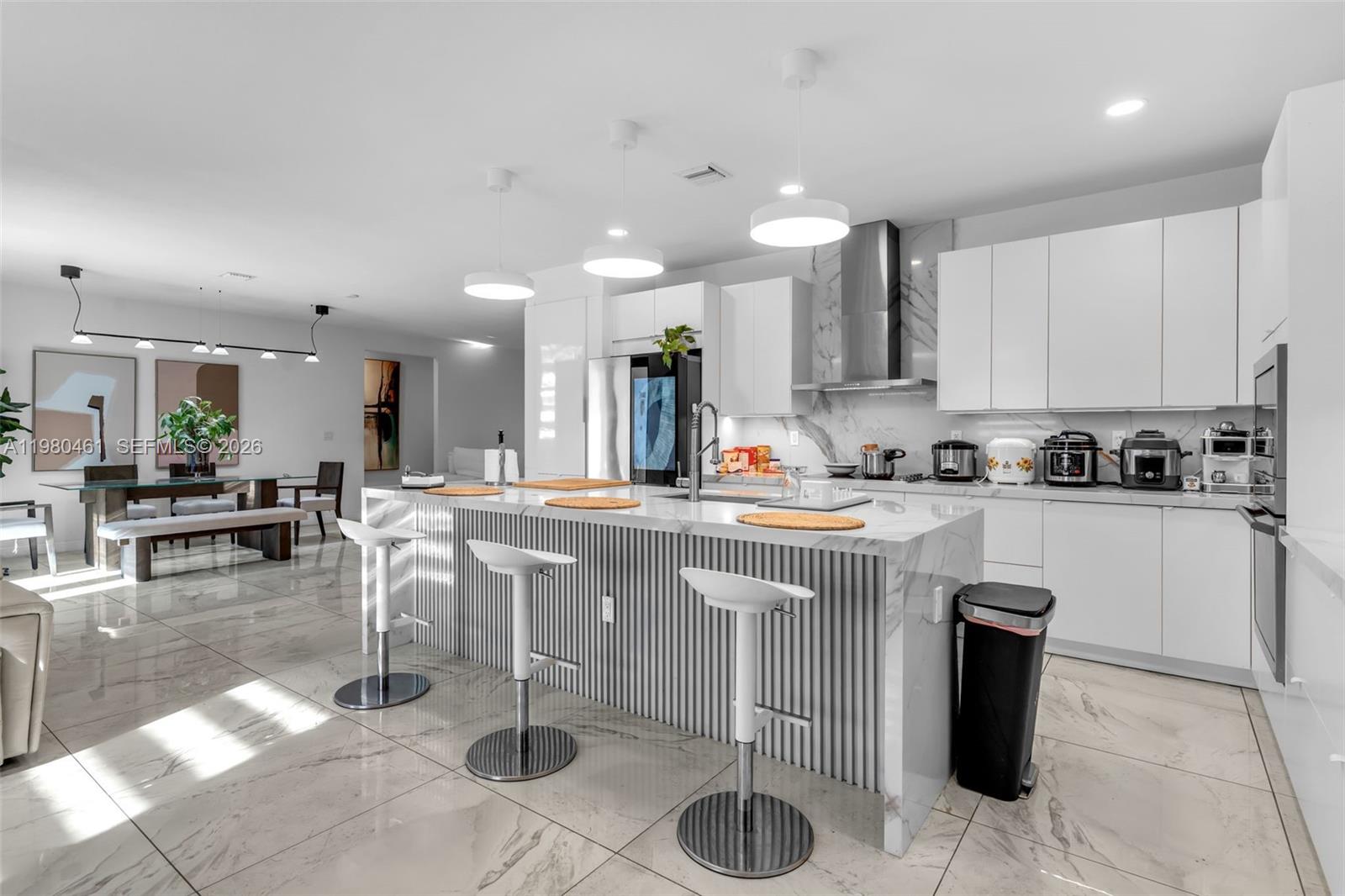 21380 Southwest 127th Place Miami, FL 33177 - Photo 13 of 47 a kitchen with stainless steel appliances kitchen island granite countertop a table and chairs in it