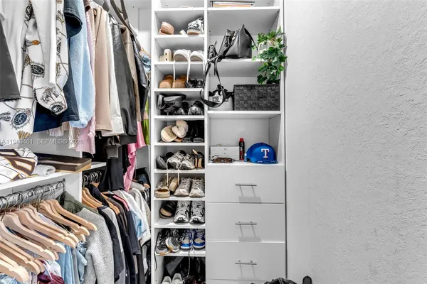 a view of walk in closet with clothes and shoes