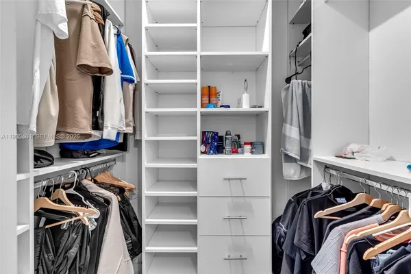 a view of walk in closet with clothes and shoes