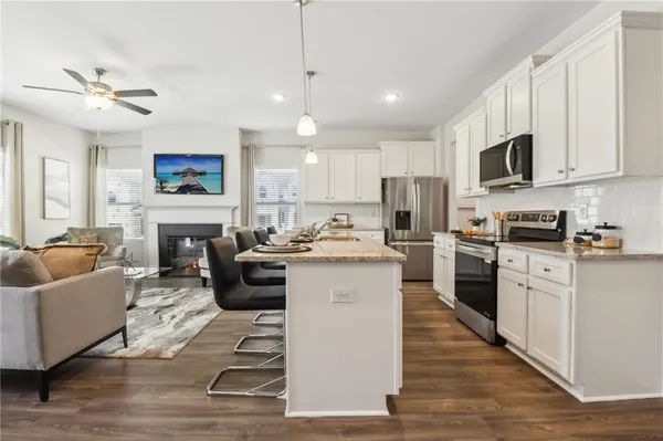 a living room with furniture a fireplace a flat screen tv and kitchen view