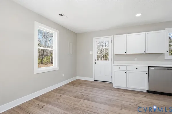 a kitchen with stainless steel appliances granite countertop a refrigerator a sink dishwasher a stove and white countertops with wooden floor