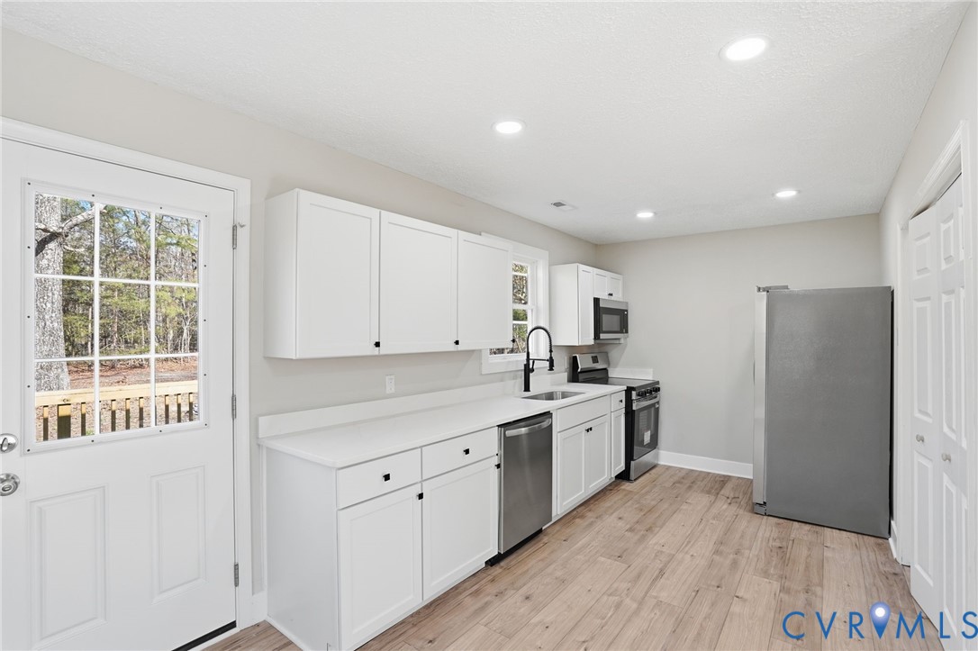 286 Mill Pond Road South St. Stephens Church, VA 23148 - Photo 10 of 39 a kitchen with stainless steel appliances granite countertop a refrigerator a sink dishwasher a stove and white countertops with wooden floor