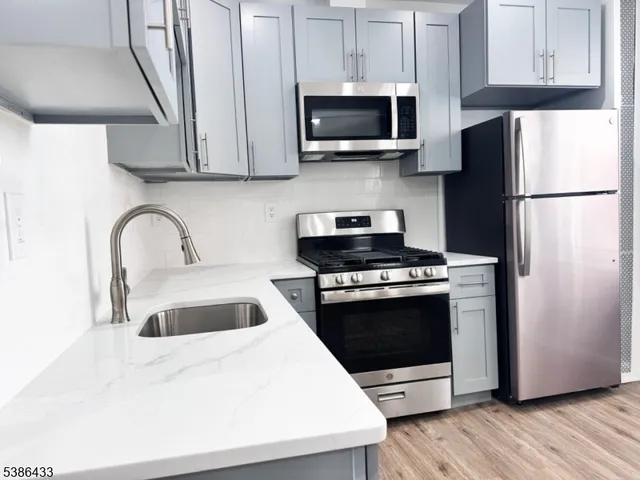 a large white kitchen with a refrigerator a stove a sink dishwasher and a oven with wooden floor