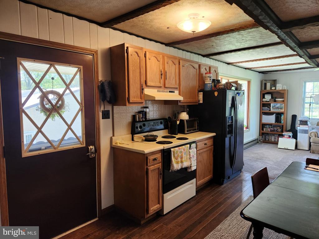 1692 Gish Road Manheim, PA 17545 - Photo 22 of 35 a kitchen with stainless steel appliances granite countertop a stove a refrigerator a sink dishwasher a dining table and chairs with wooden floor
