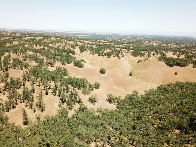 an aerial view of house with yard and mountain view in back