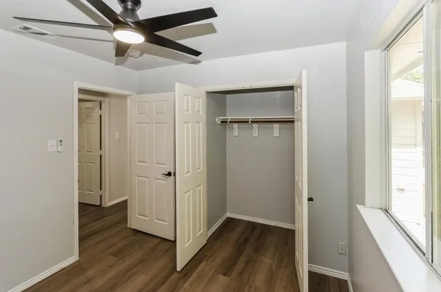 a view of empty room with wooden floor and fan