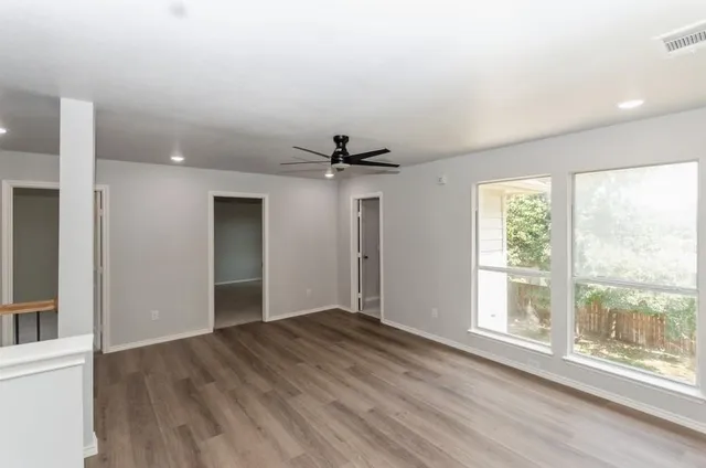 a view of an empty room with a window and wooden floor