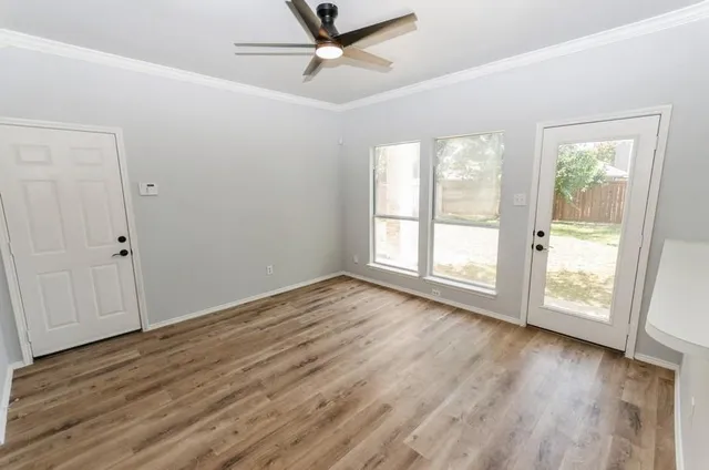 an empty room with wooden floor fan and windows