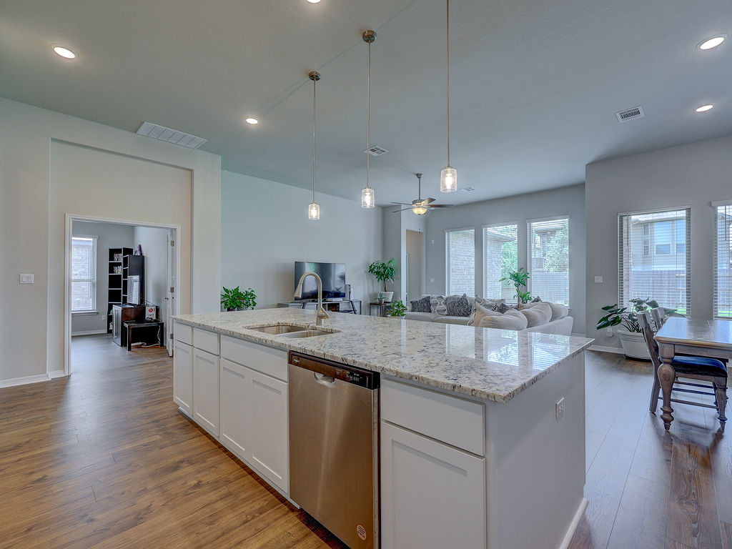 229 Heartleaf Road San Marcos, TX 78666 - Photo 15 of 40 An inviting open-concept space features a pristine kitchen island with granite counters and rich hardwood flooring.