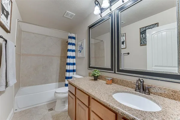 a bathroom with a granite countertop sink a toilet a mirror a bathtub and shower