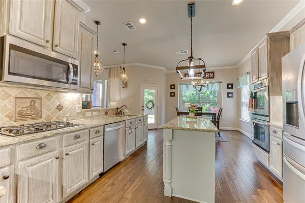 a kitchen with stainless steel appliances kitchen island granite countertop a stove a sink and a refrigerator