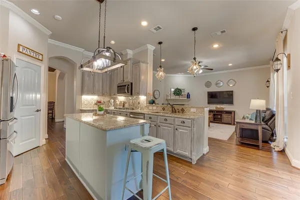 a kitchen with stainless steel appliances kitchen island granite countertop a table chairs and a chandelier