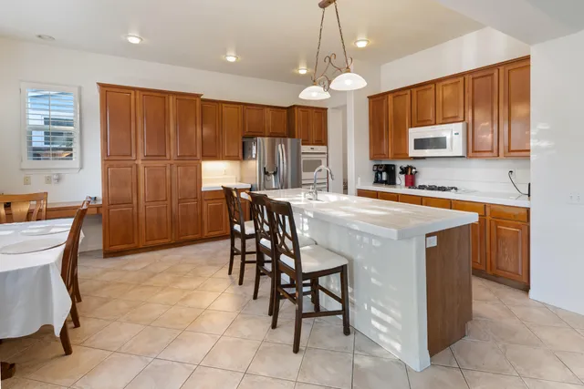 a kitchen with stainless steel appliances granite countertop a table chairs sink and cabinets