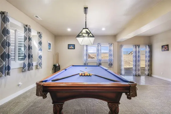 a living room with pool table and windows