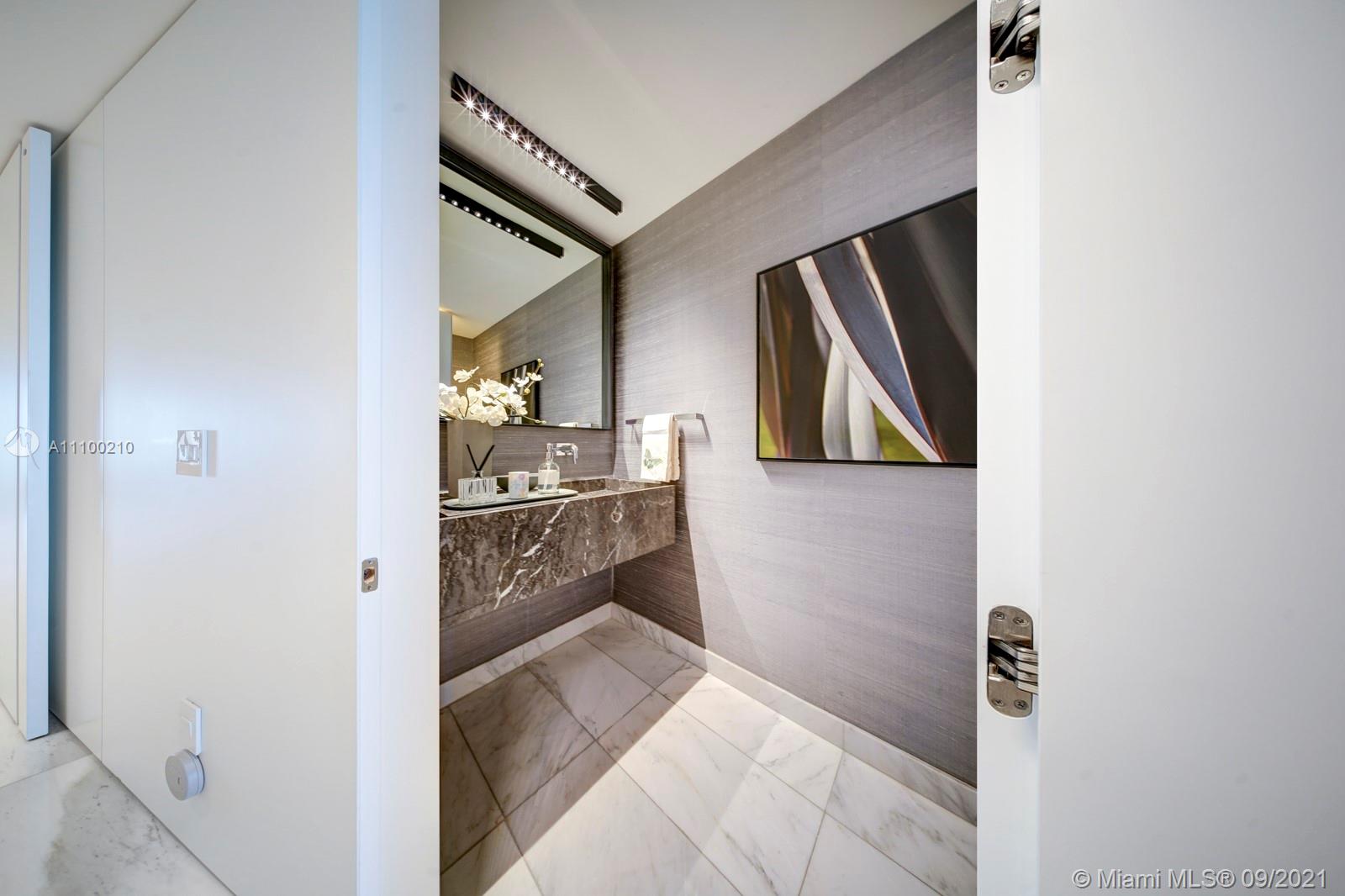 10203 Collins Avenue, Unit 1802 Bal Harbour, FL 33154 - Photo 13 of 43 a hallway with painting on the wall and a mirror