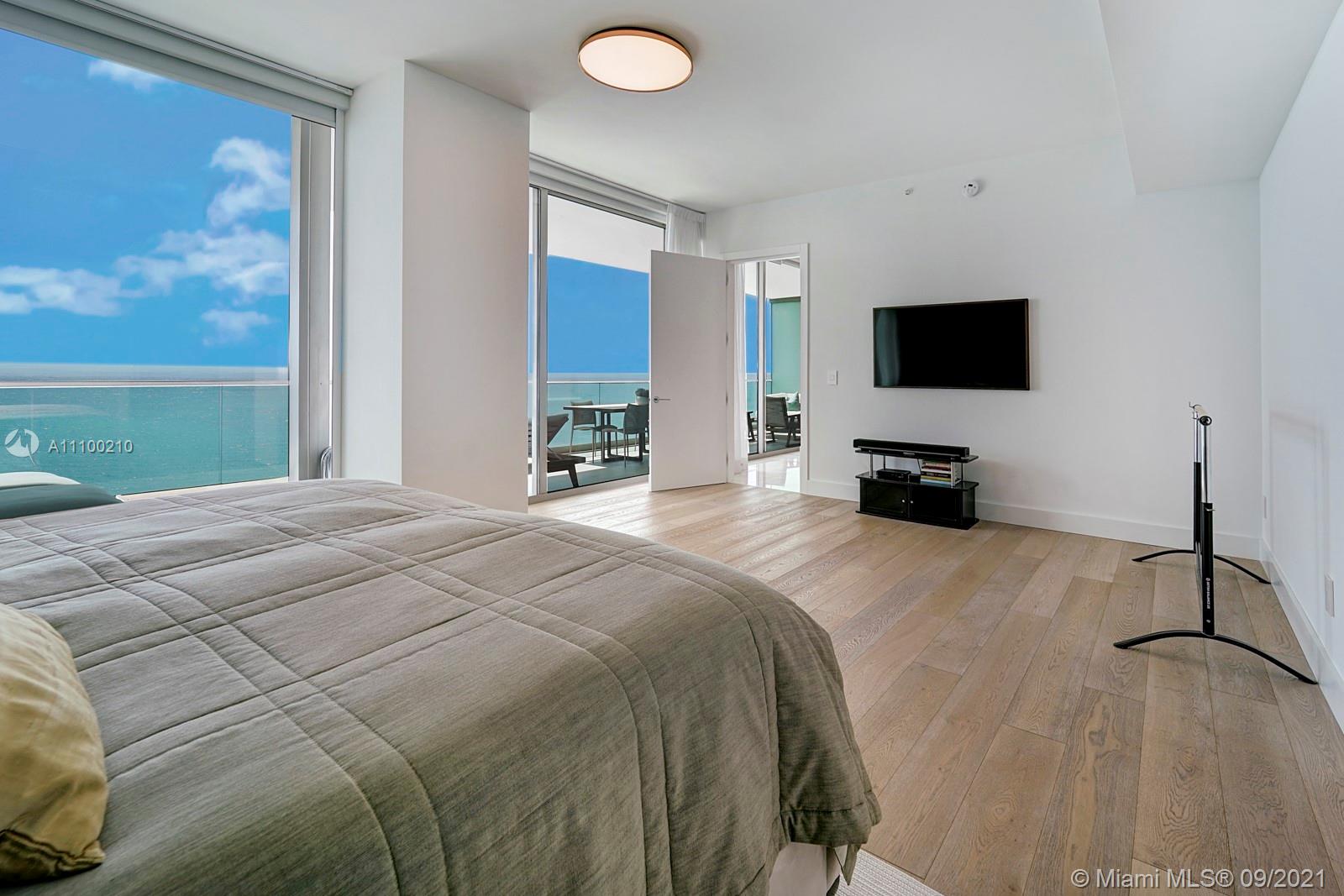 10203 Collins Avenue, Unit 1802 Bal Harbour, FL 33154 - Photo 26 of 43 a bedroom with a bed a television and a large window
