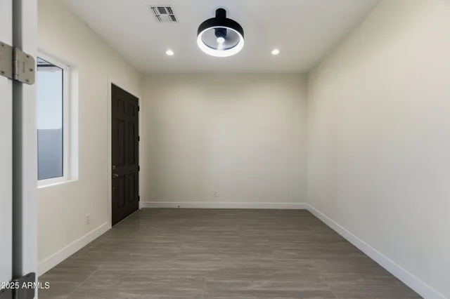 a view of an empty room with a window and a kitchen