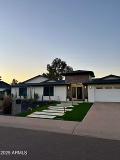 a view of a house with a yard potted plants and a table