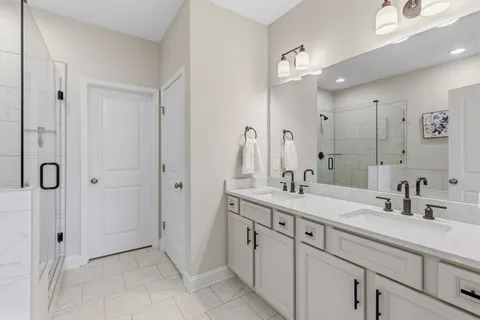 a spacious bathroom with a double vanity sink a mirror and shower
