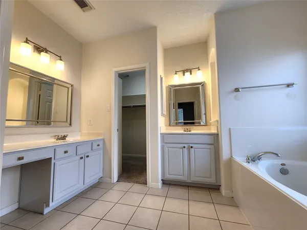 a spacious bathroom with a granite countertop sink a mirror and bathtub