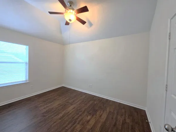 an empty room with a window and a fan