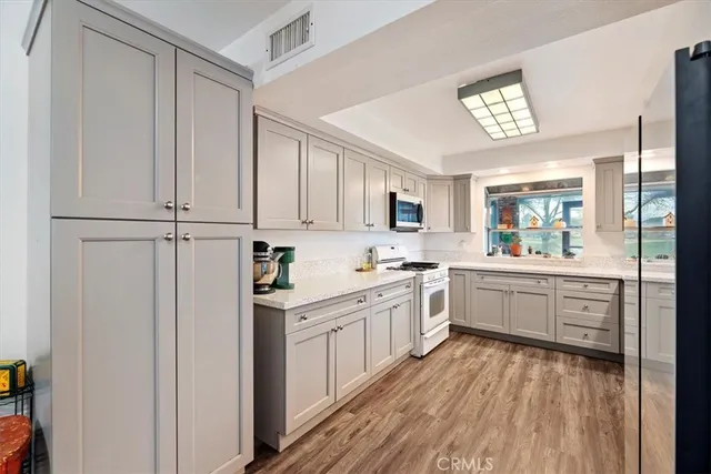a kitchen with stainless steel appliances granite countertop a stove a sink and white cabinets with wooden floor