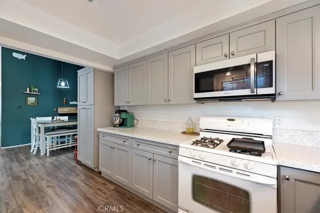 a kitchen with cabinets stainless steel appliances and wooden floor