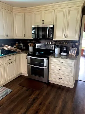 a kitchen with granite countertop a stove and a microwave