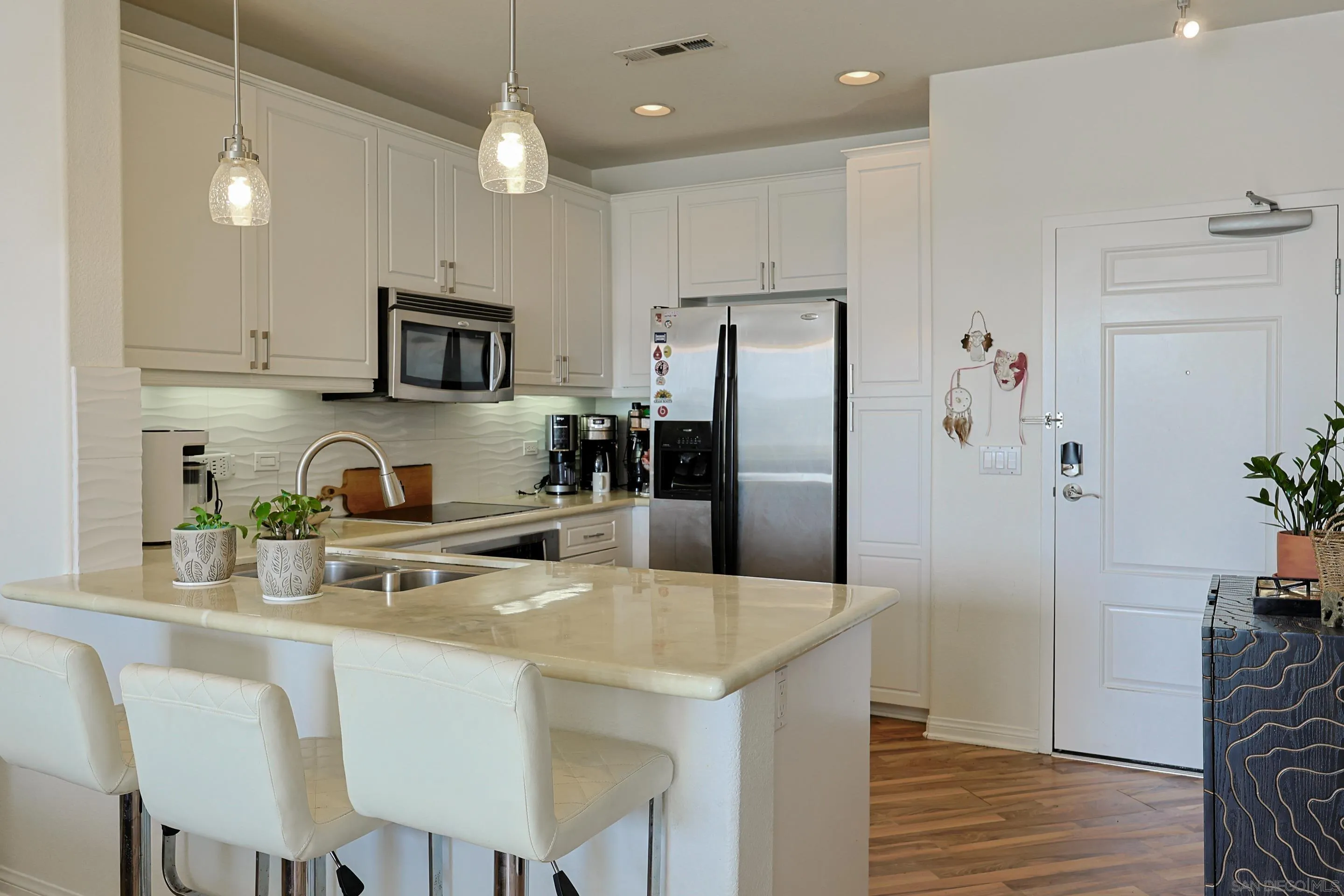 3887 Pell Place, Unit 229 San Diego, CA 92130 - Photo 7 of 49 a kitchen with kitchen island granite countertop a refrigerator stove microwave and white cabinets