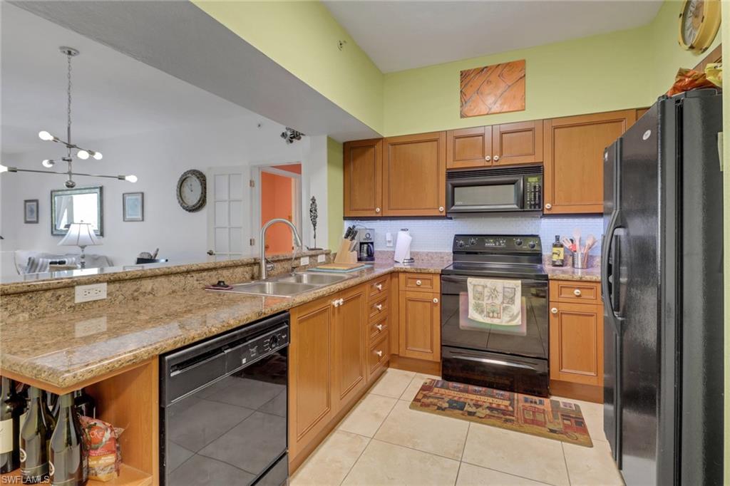 20140 Estero Gardens Circle, Unit 101 Estero, FL 33928 - Photo 3 of 40 a kitchen with stainless steel appliances granite countertop a sink a stove and a refrigerator