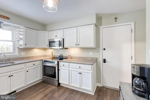 a kitchen with stainless steel appliances granite countertop a sink and cabinets with wooden floor