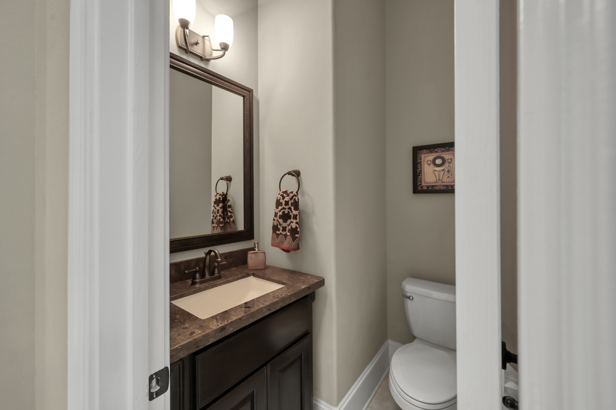 26 Woodborough Way Spring, TX 77389 - Photo 15 of 43 This charming powder bath combines elegance and functionality with its sleek dark vanity, modern fixtures, and warm lighting, perfect for stylish convenience.