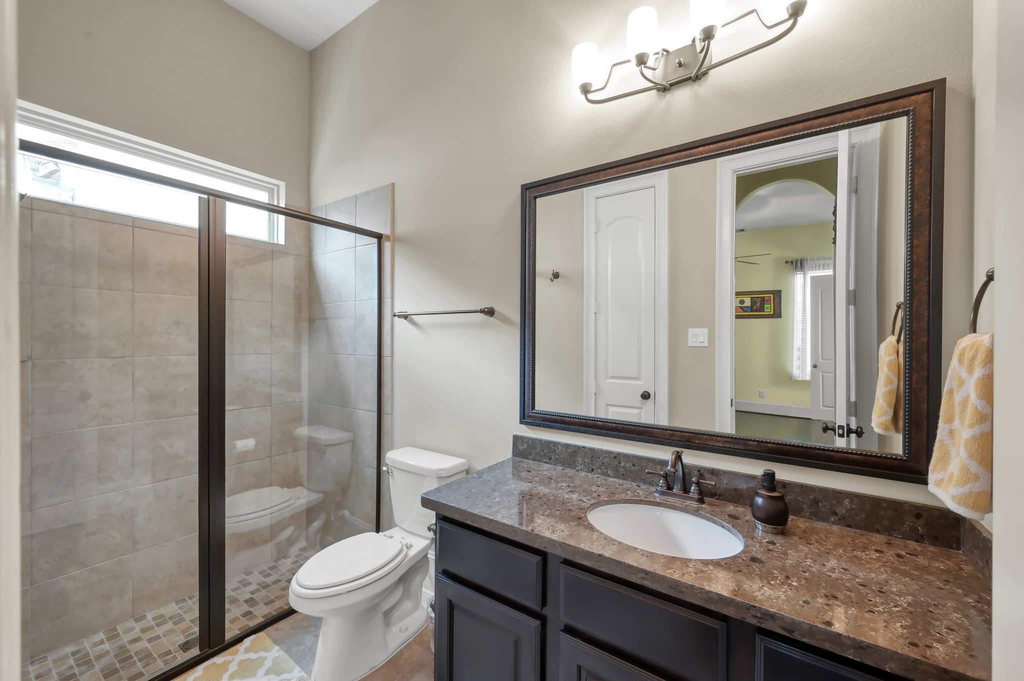 26 Woodborough Way Spring, TX 77389 - Photo 24 of 43 Experience ultimate convenience and style in this private en-suite bath, featuring a sleek glass shower, elegant tile flooring, and a modern vanity, perfectly complementing the additional downstairs bedroom.