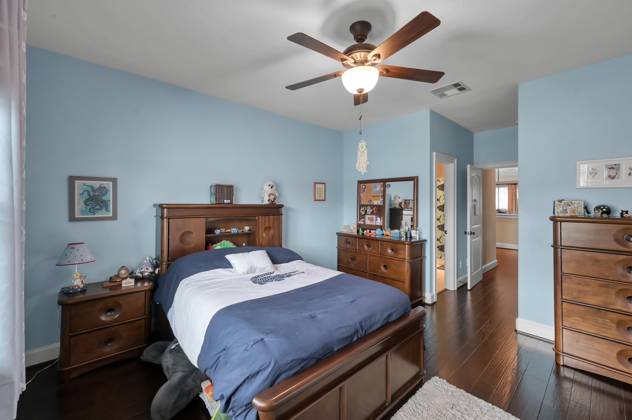 26 Woodborough Way Spring, TX 77389 - Photo 27 of 43 This bedroom features soft blue walls and dark wood flooring, complemented by a ceiling fan. All of the bedrooms have access to their own bathroom.