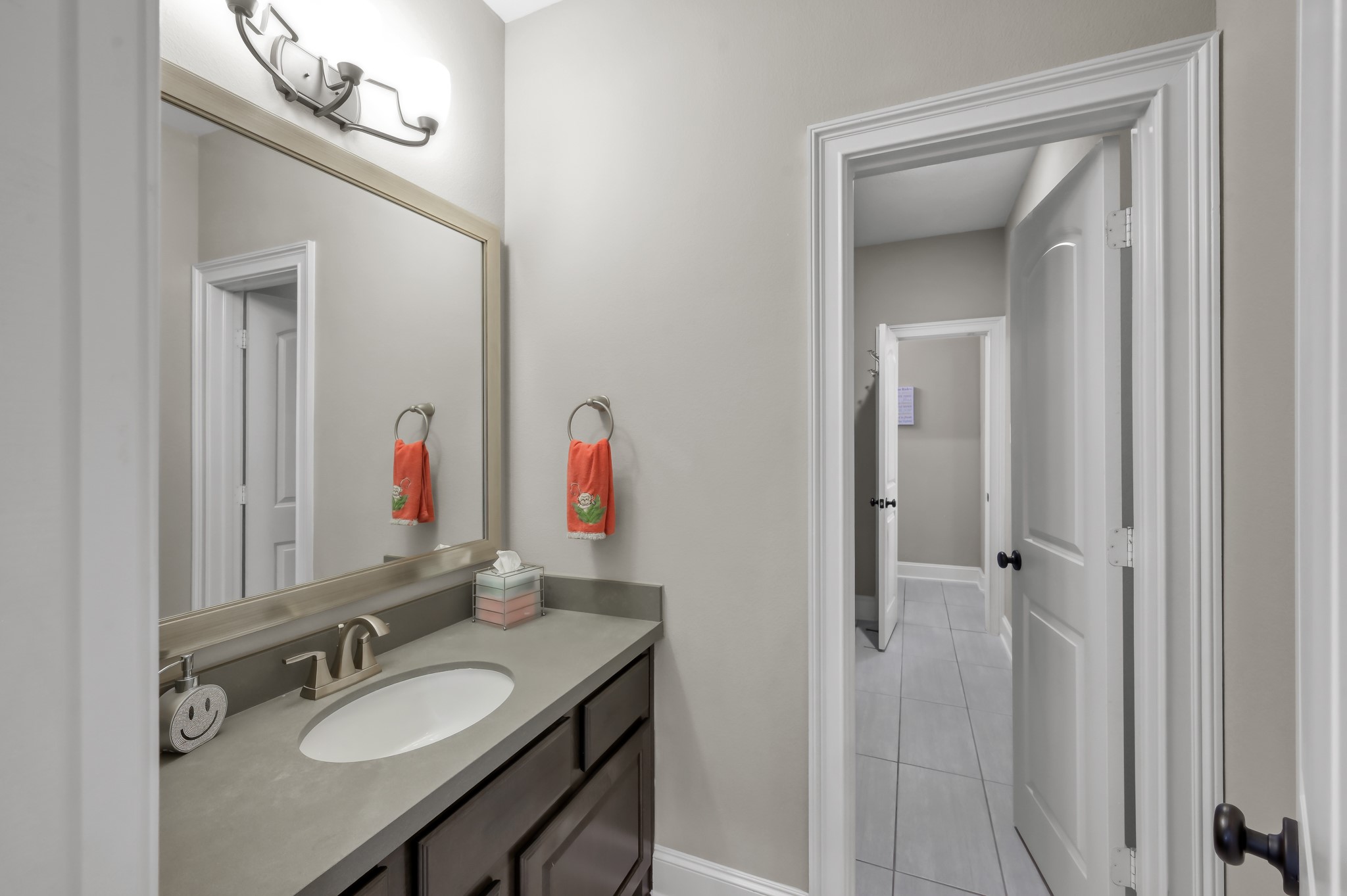 26 Woodborough Way Spring, TX 77389 - Photo 30 of 43 This photo showcases a modern bathroom with a sleek countertop and sink, a large framed mirror, and elegant lighting. This is the bathroom upstairs that is a jack and jill bathroom which allows guests who are using media room upstairs to access a bathroom thru the hallway.